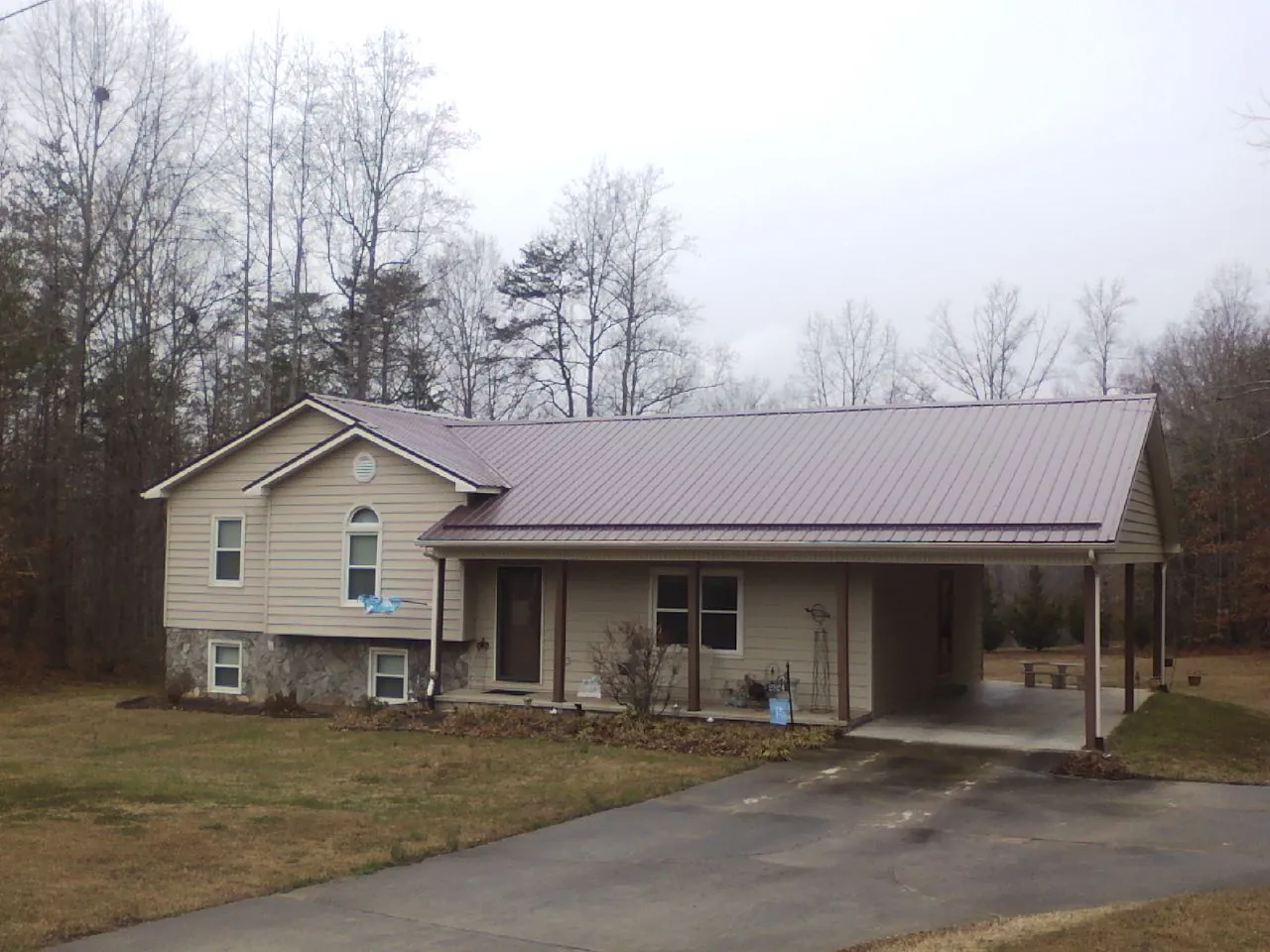 Burgundy metal roof on a tan split level home with an attached carport in Hillsdale