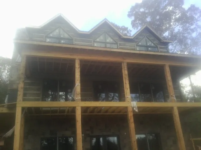 Dormers and porch framing on a large log home under construction — Roof Coating work by our crew in Hillsdale